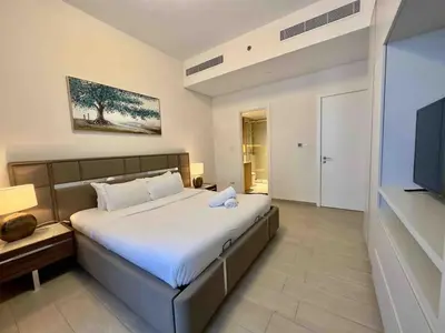 a bedroom with a large bed and a flat screen tv at Spacious & Modern 1BR in Wilton Terraces in Dubai