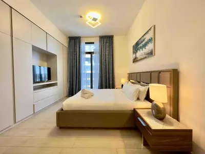 a bedroom with a large bed and a tv at Spacious & Modern 1BR in Wilton Terraces in Dubai