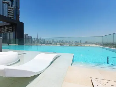 a large swimming pool with a white chair on a building at Modern Neoclassical 1BR - Berkeley Place Dubai in Dubai