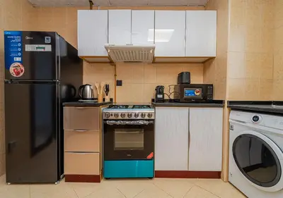 a kitchen with a stove and a refrigerator and a dishwasher at Lux JVT Resort Pools Spa Gym Kids Play in Dubai