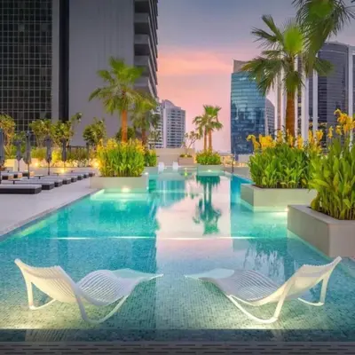 a swimming pool with two chairs in a building at Elegant Designer Studio8 Min Walk to Burj Khalifa in Dubai