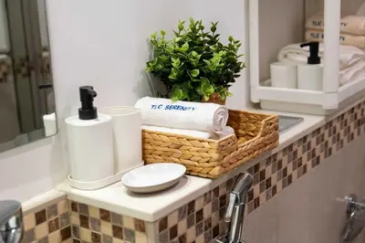 a bathroom counter with a basket of towels and a mirror at Cozy Burj Khalifa View Retreat in Dubai