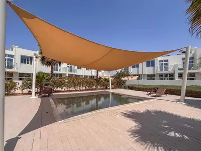 a pool in a courtyard with a large umbrella at Frank Porter - Avencia, Damac Hills 2 in Dubai