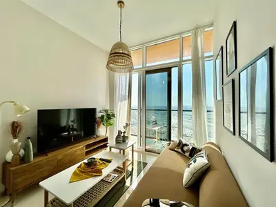a living room with a couch and a large window at Homes2Retreat - Golf & Desert Views - Luxe 1BR Escape in Dubai