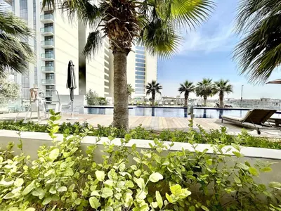 a resort with a pool and palm trees and a building at Homes2Retreat - Golf & Desert Views - Luxe 1BR Escape in Dubai