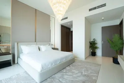 a bedroom with a white bed and a chandelier at KeyRock - Palm & Sea View Apt at Grand Bleu in Dubai