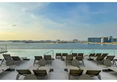 a row of chairs and tables on a patio next to the water at KeyRock - Sea View Stay with Pool Access in Dubai