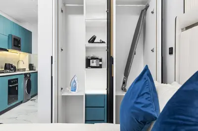 a room with blue cabinets and a bed with a mirror at ALiving Modern Studio I Private Pool I Opalz by Danube- 1308 in Dubai