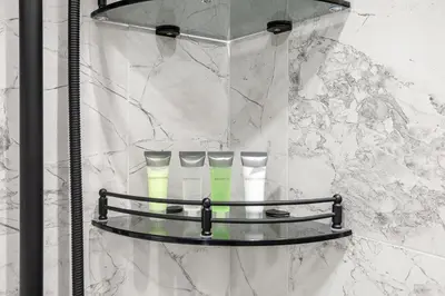 a shelf in a shower with three tubes of toothbrushes at ALiving Modern Studio I Private Pool I Opalz by Danube- 1308 in Dubai