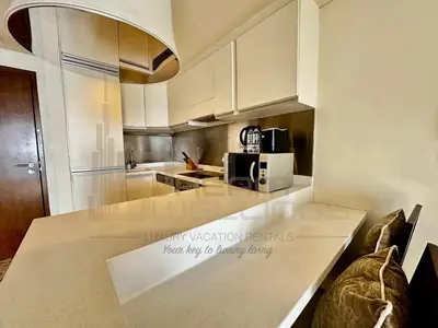 a kitchen with white cabinets and a counter top at Kempinski Central Avenue Studio Burj view in Dubai