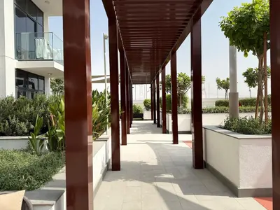 a walkway in a building with columns and plants at ASHRI HH Condo In Riviera Meydan in Dubai