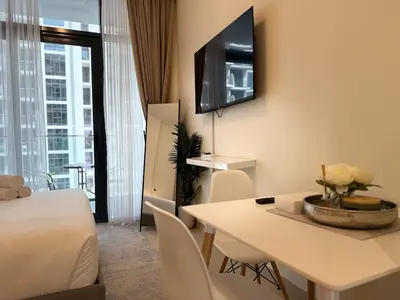 a hotel room with a bed and a table with chairs at ASHRI HH Condo In Riviera Meydan in Dubai