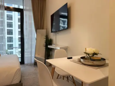 a living room with a table with a vase of flowers on it at ASHRI HH Condo In Riviera Meydan in Dubai