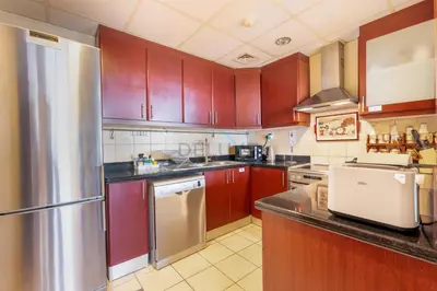 a kitchen with wooden cabinets and a stainless steel refrigerator at Ain Dubai & Sea Views 2BR Unit Close to Beach, Shams 4, Jumeirah Beach Residence by Deluxe Holiday Homes in Dubai