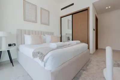 a white bedroom with a large bed and a desk at TRPS - Binghatti Amber, JVC - Luxury 1BR Haven - Prime Location in Dubai