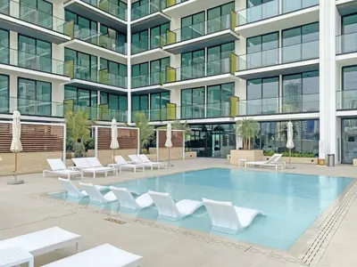 a large building with a swimming pool with white chairs at TRPS - Binghatti Amber, JVC - Luxury 1BR Haven - Prime Location in Dubai