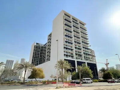 a tall white building with palm trees in front of a city at TRPS - Binghatti Amber, JVC - Luxury 1BR Haven - Prime Location in Dubai