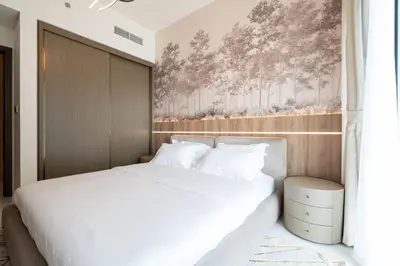 a bedroom with a white bed and a wall at KeyRock - Stylish 2BR Apt with Palm Jumeirah View, Balcony , Pool & Gym Access in Dubai