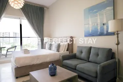 a bedroom with a bed and a couch and a table at Modern Studio 10 Mints Away From Expo Pool & Gym in Dubai