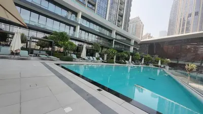 a large building with a large blue swimming pool at Luxe 1 Bedroom with High Floor close to Dubai Mall in Dubai