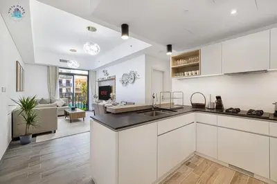 a kitchen with white cabinets and a living room at Furnished 2BR with Vibrant View in Dubai