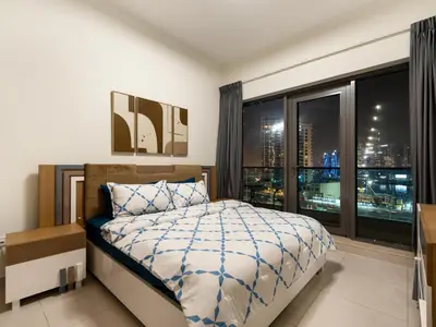 a bedroom with a bed and a large window at Luxury 2BR near Burj Khalifa with Rooftop Pool, City & Canal Views, Free Parking in Dubai