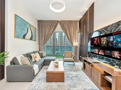 a living room with a couch and a tv at Modern 1BR Near Burj Khalifa with Rooftop Pool, City & Canal Views, Free Parking in Dubai