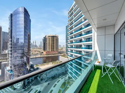 a balcony with chairs and a view of a city at Modern 1BR Near Burj Khalifa with Rooftop Pool, City & Canal Views, Free Parking in Dubai