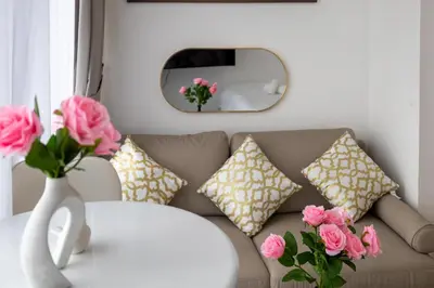 a living room with a couch and a vase with pink roses at Luxe Studio Vibes Stylish & All New Pet Free in Dubai