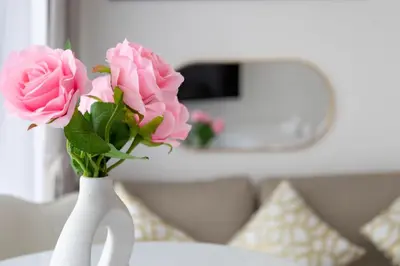 a white vase filled with pink roses on a table at Luxe Studio Vibes Stylish & All New Pet Free in Dubai