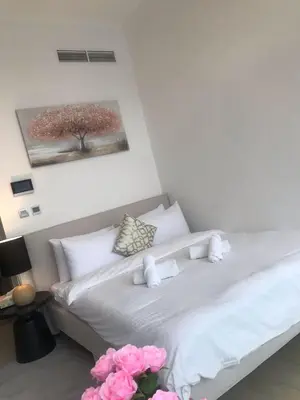 a bedroom with a white bed with pink flowers at Luxe Studio Vibes Stylish & All New Pet Free in Dubai