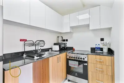 a kitchen with white cabinets and a stove top oven at Bookable -1 Bed Rukan Townhouse with Clubhouse Access in Dubai
