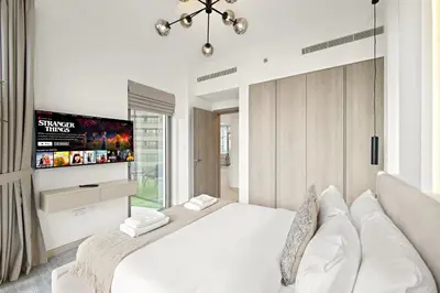 a bedroom with a white bed and a flat screen tv at Luxe 2BR with Marina Views l Gaming & Music Room in Dubai