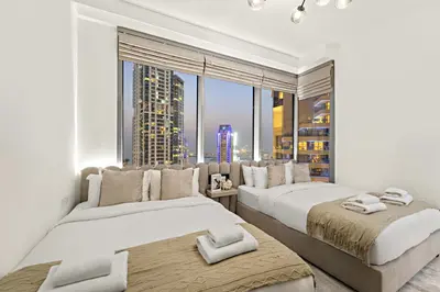two beds in a room with a large window at Luxe 2BR with Marina Views l Gaming & Music Room in Dubai