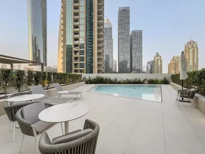 a rooftop patio with tables and chairs and a pool at Luxe 2BR with Marina Views l Gaming & Music Room in Dubai