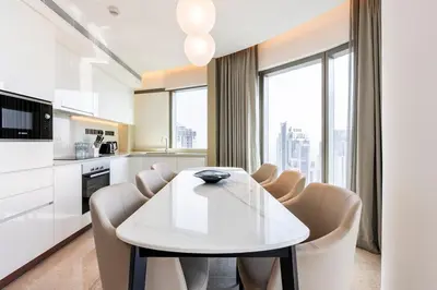 a white kitchen with a white table and chairs at Iconic 3BHK I Stunning Creek Views I Sleep up to 6 guests I High Floor I Pool I Free Parking I Pet Friendly I in Dubai