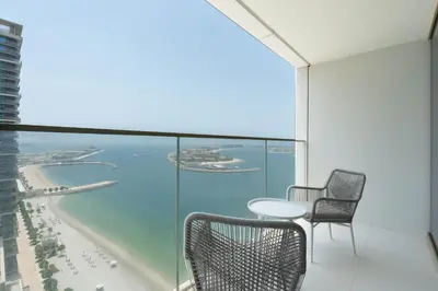 a balcony with a table and chairs and the ocean at Keyrock - Emaar Beachfront Apartment with Sea & Palm Jumeirah Views in Dubai