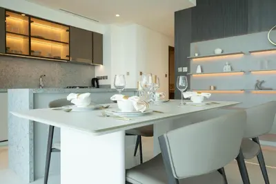 a kitchen with a white table with chairs and wine glasses at Keyrock - Emaar Beachfront Apartment with Sea & Palm Jumeirah Views in Dubai