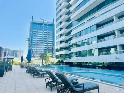 a swimming pool with lounge chairs next to a building at Luxurious 1BR , Damac Maison Canal Views in Dubai