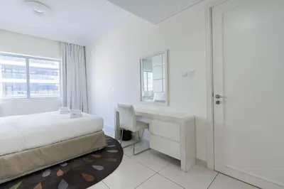 a white bedroom with a desk and a bed at TRPS - Maison Mall Street, Downtown - Beautifully Appointed 1BR, Near to Burj Khalifa in Dubai