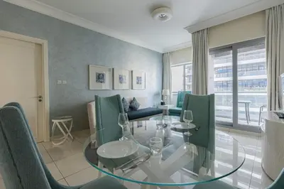 a dining room with a glass table and green chairs at TRPS - Maison Mall Street, Downtown - Beautifully Appointed 1BR, Near to Burj Khalifa in Dubai