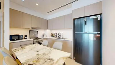 a kitchen with a table and a refrigerator at Exclusive Burj Khalifa View Luxury 2BR Next to Dubai Mall - Like Home in Dubai