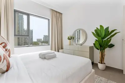 a white bedroom with a white bed and a large window at Radiant 2BR APT near Dubai Hills Park & Golf Club in Dubai