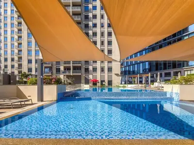 a large swimming pool with blue tiles in a building at Radiant 2BR APT near Dubai Hills Park & Golf Club in Dubai