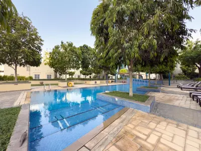a swimming pool in a park with a tree at GuestReady - Downtown View | 1BR + Sofa Bed in Dubai