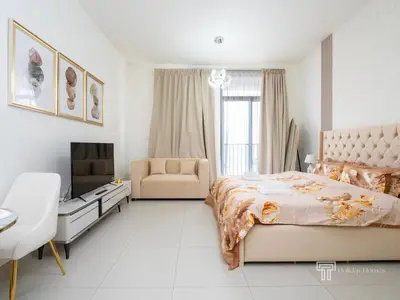 a bedroom with a bed and a couch and a television at Brand New High Floor Studio in Midtown Dubai in Dubai