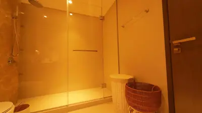 a glass shower in a bathroom with a trash can at Elegant Seaside Luxury 1BR in Beachfront, Grand BLeu Tower, Pool & Gym in Dubai