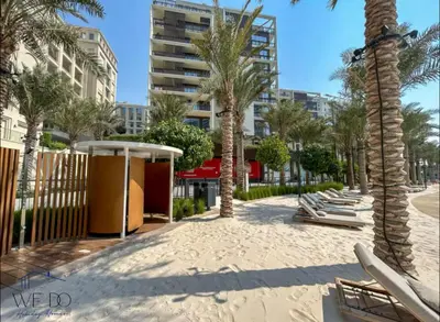 a sandy beach with palm trees and lounge chairs at Luxury Apartment in CREEK Harbour in Dubai
