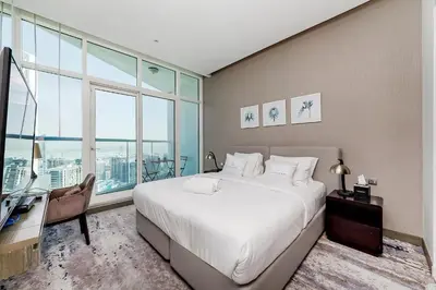 a bedroom with a large bed and a desk and window at Studio Apartments with City View at DAMAC Maison Prive in Dubai
