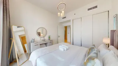 a white bedroom with a bed and a mirror at Beach Vista - One Bed with Infinity Pool Access in Dubai